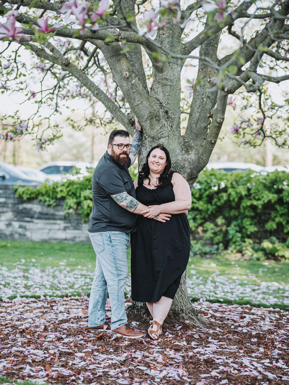 Spring engagement photos taken under blooming cherry blossom trees in a park.