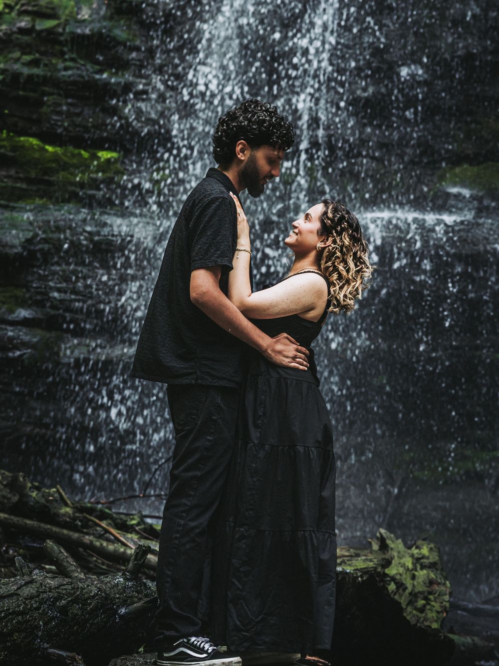 Couple sharing tender moments against a cascading waterfall backdrop.