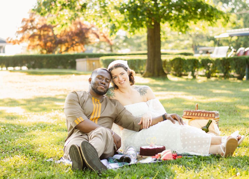 A couple enjoys a romantic picnic on the grass under a shady tree.