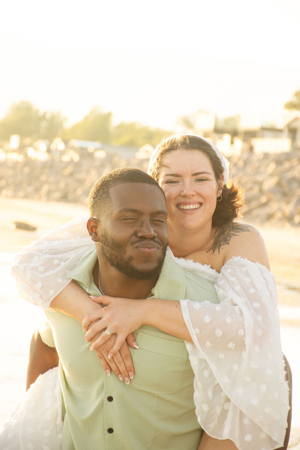 A couple embraces and smiles during golden hour at the beach.