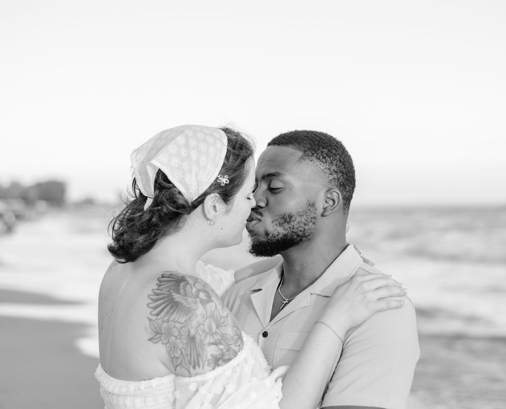 Romantic black and white photo of a couple sharing a tender moment by the ocean.