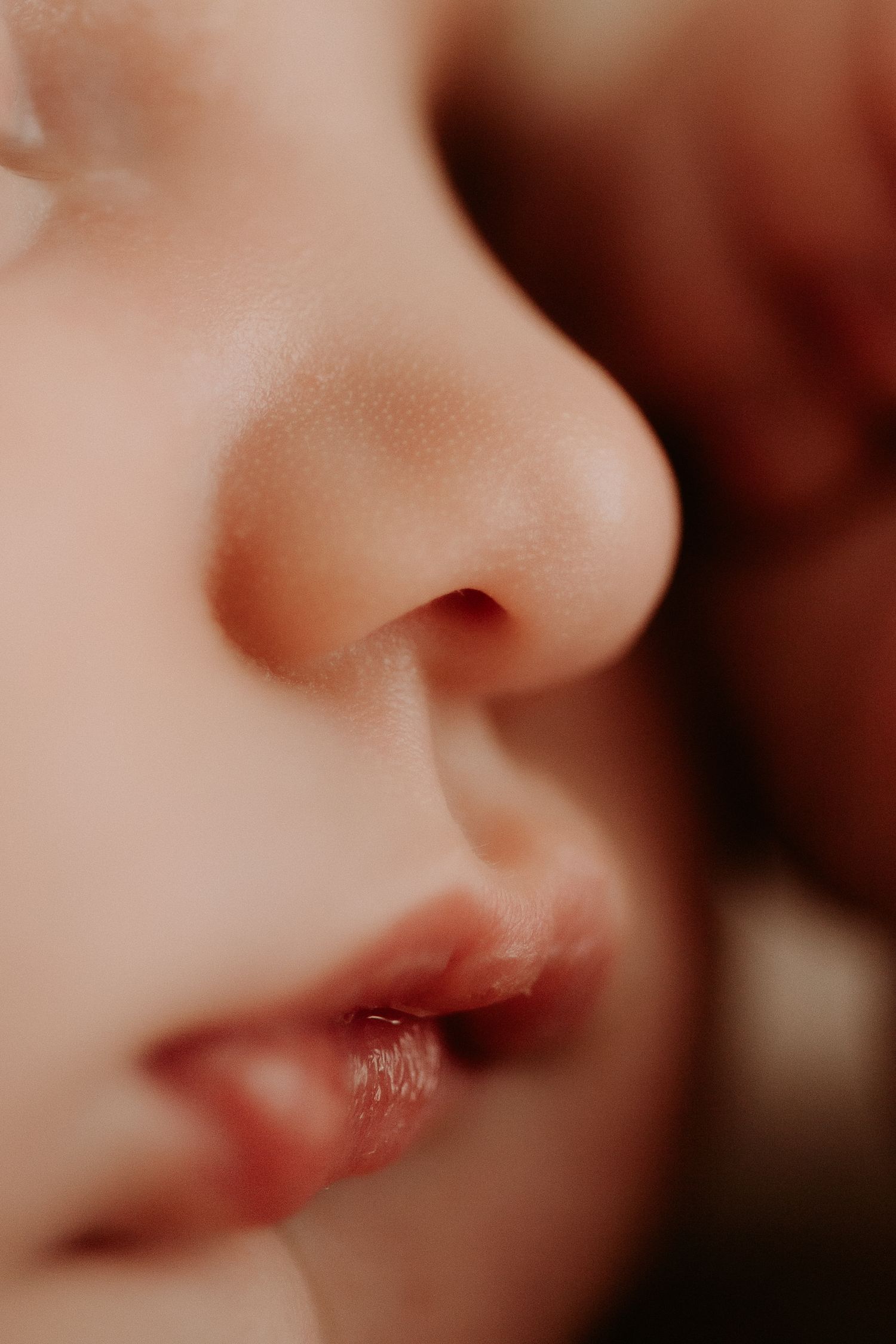 Close-up macro photo of a child's nose and lips with soft, glowing skin in warm natural light.