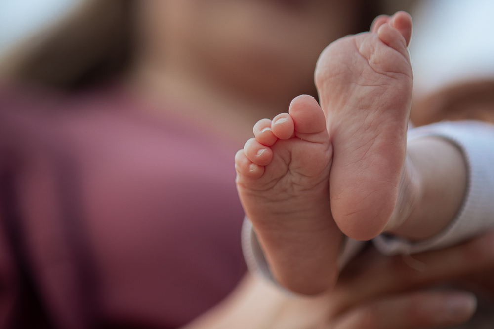 Close-up van babyvoetjes vastgehouden door een ouder.