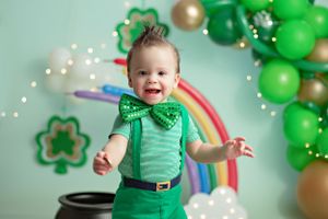 St Patrick's Day celebration scene with rainbow, shamrocks, and festive green balloon arch decorations.