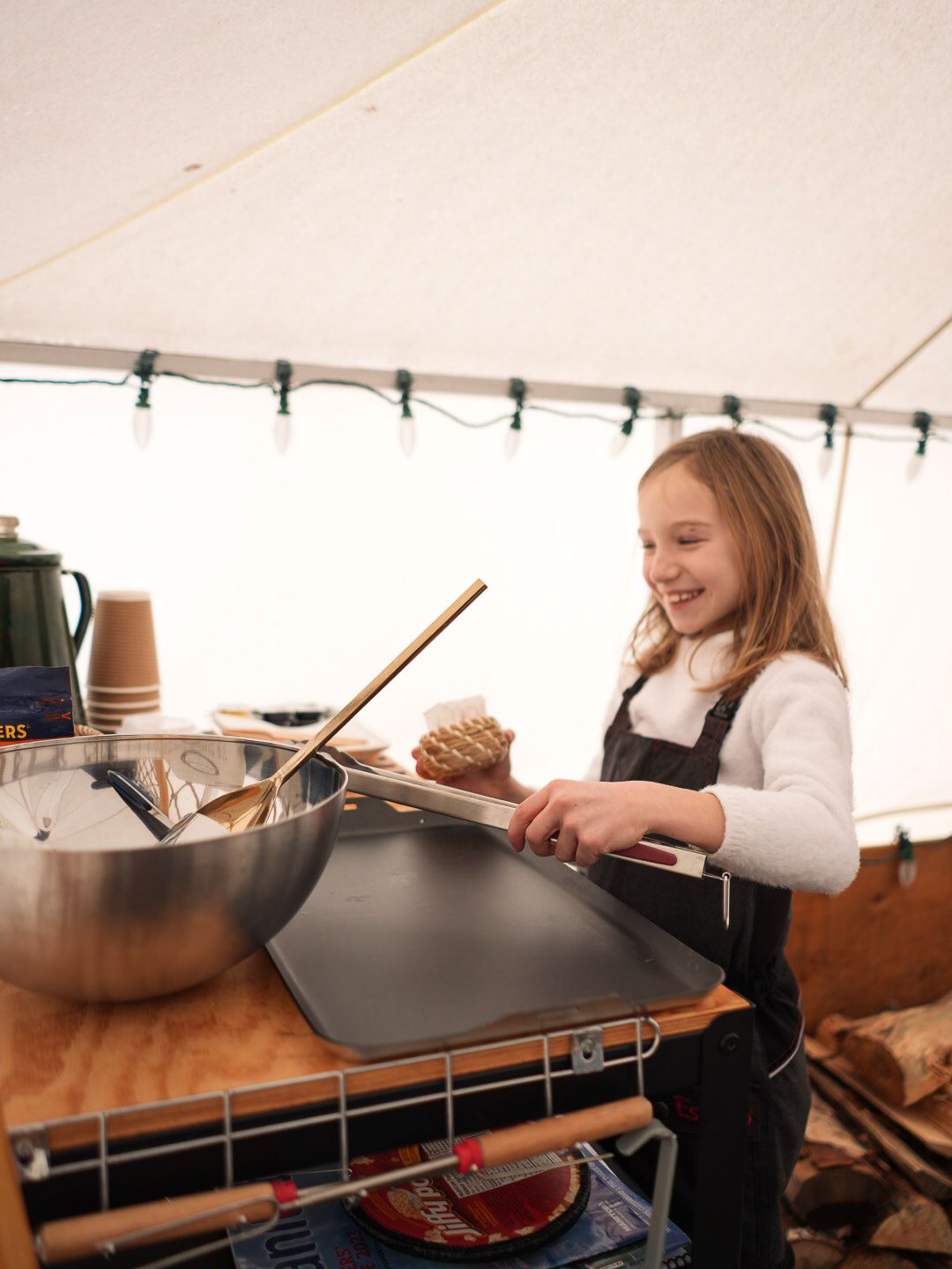 Art supplies and drawing materials arranged on a wooden surface in a tent.
