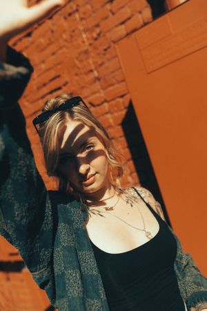 Series of artistic portrait shots against an orange brick wall showcasing dynamic shadows and angles in warm lighting.