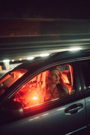 Dramatic nighttime shot of a car interior illuminated by red light through the driver's side window.