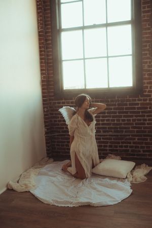 A series of artistic poses in white dress against exposed brick wall with natural window light.