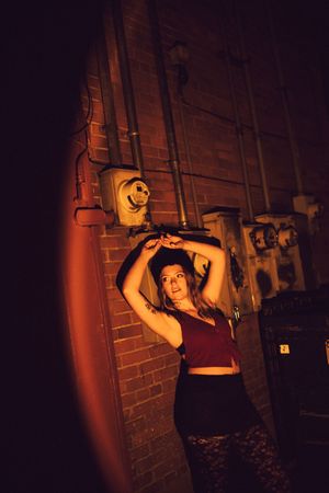 Dramatic red-lit sequence showing dance movements against a brick wall background.