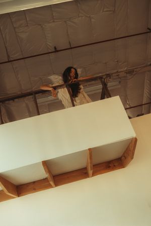 A sequence of photos showing someone emerging through a white ceiling panel in an artistic performance.