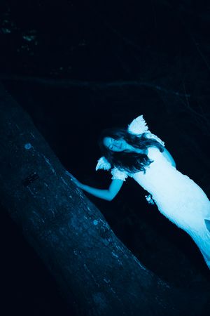 Artistic blue-tinted photos capture a figure floating in darkness with flowing white fabric.