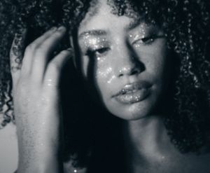 Black and white photo series showing close up portraits of a person with curly hair and glowing glitter makeup details.