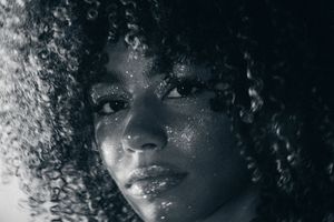 A series of black and white portrait photos showing curly hair and dramatic lighting effects.