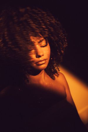 Artistic portrait series showing silhouette in dramatic orange lighting with curly hair against dark background.