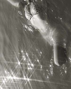 Light reflecting off rippling water creates a mesmerizing pattern of sparkling starbursts in black and white.