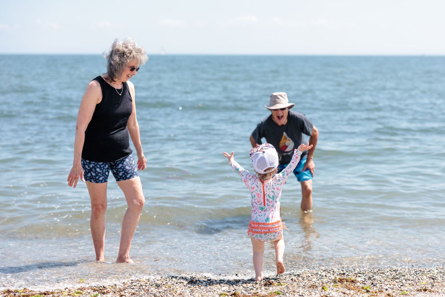 Family enjoying a sunny day at the beach with waves crashing in the background.