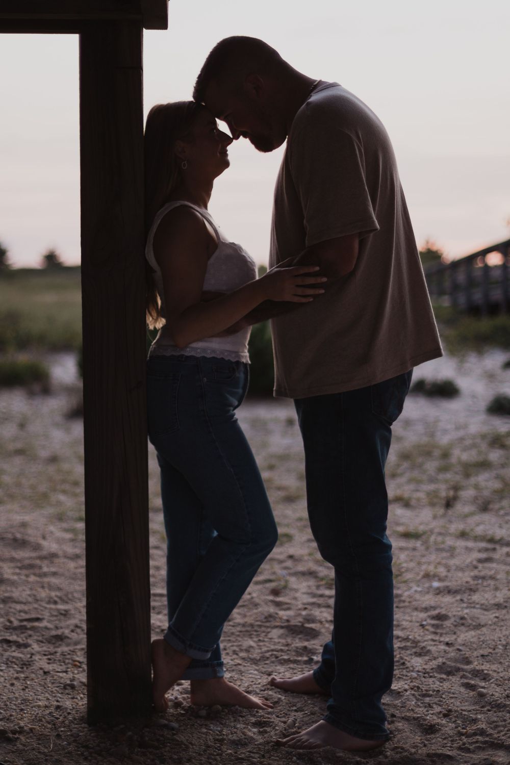A silhouetted couple shares an intimate moment while standing together at dusk.