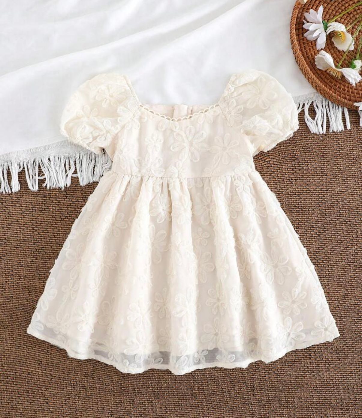 White lace ruffle skirt with delicate embroidery details displayed on brown background.