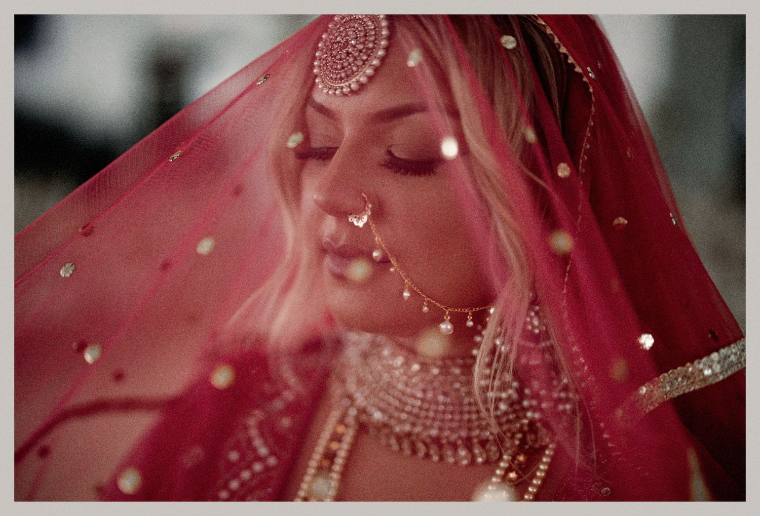 Close-up of a red bridal veil with intricate jewelry details and sparkles.