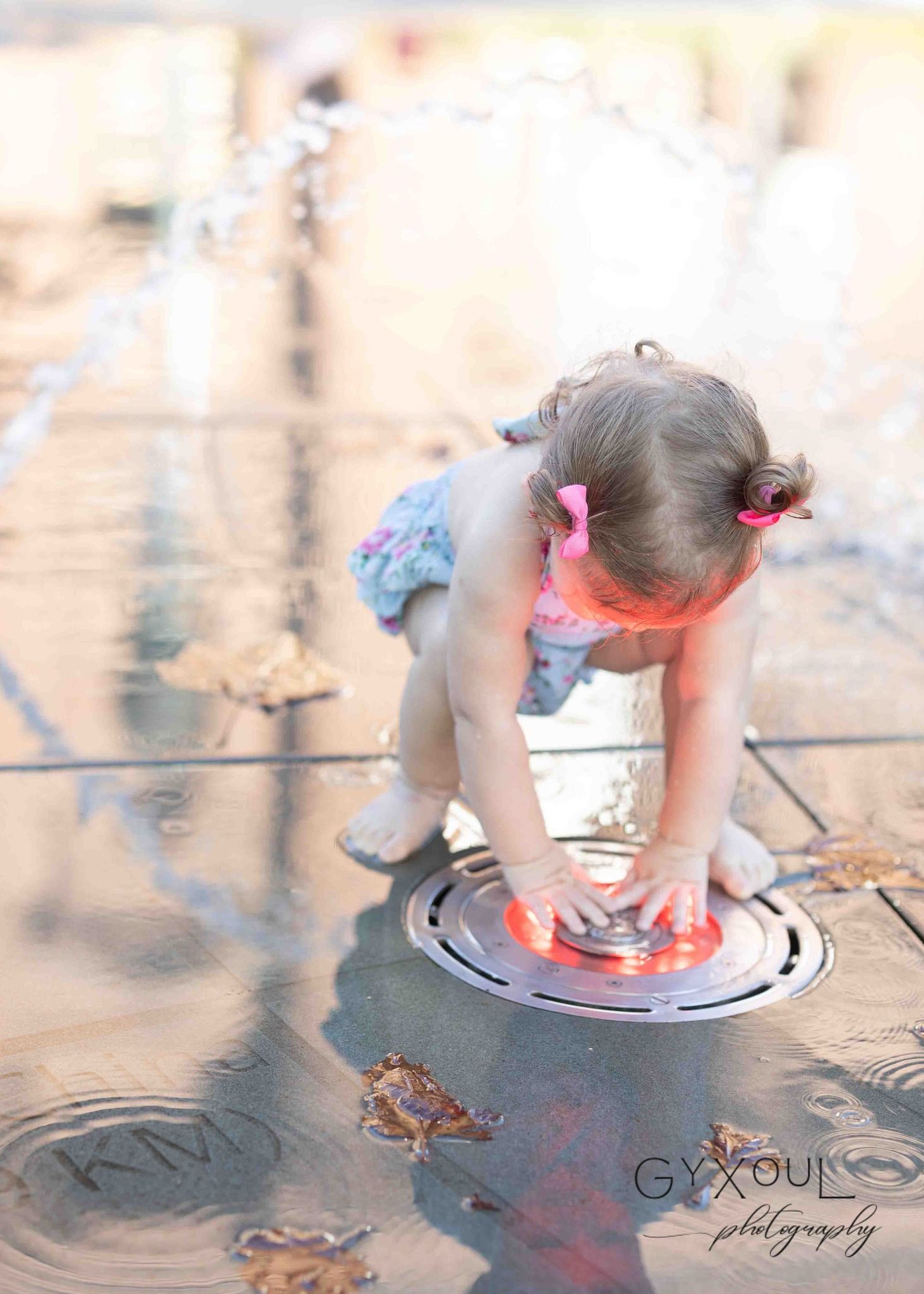 Child in blue floral outfit touching reflective surface in artistic outdoor photo.