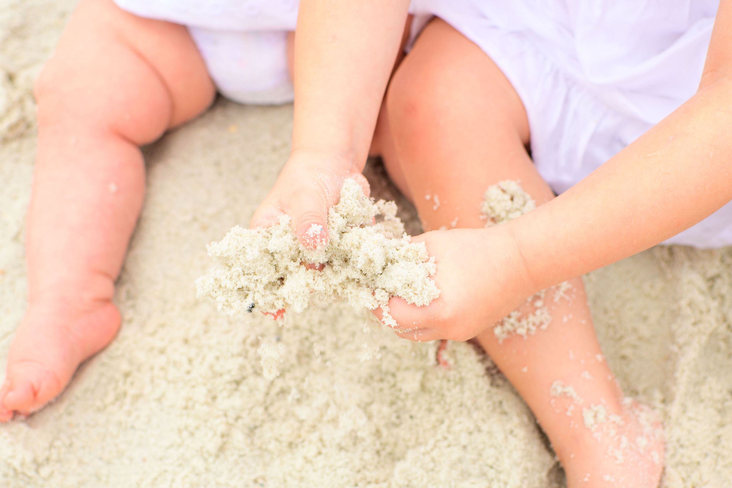 Close-up of small hands playing with beach sand.