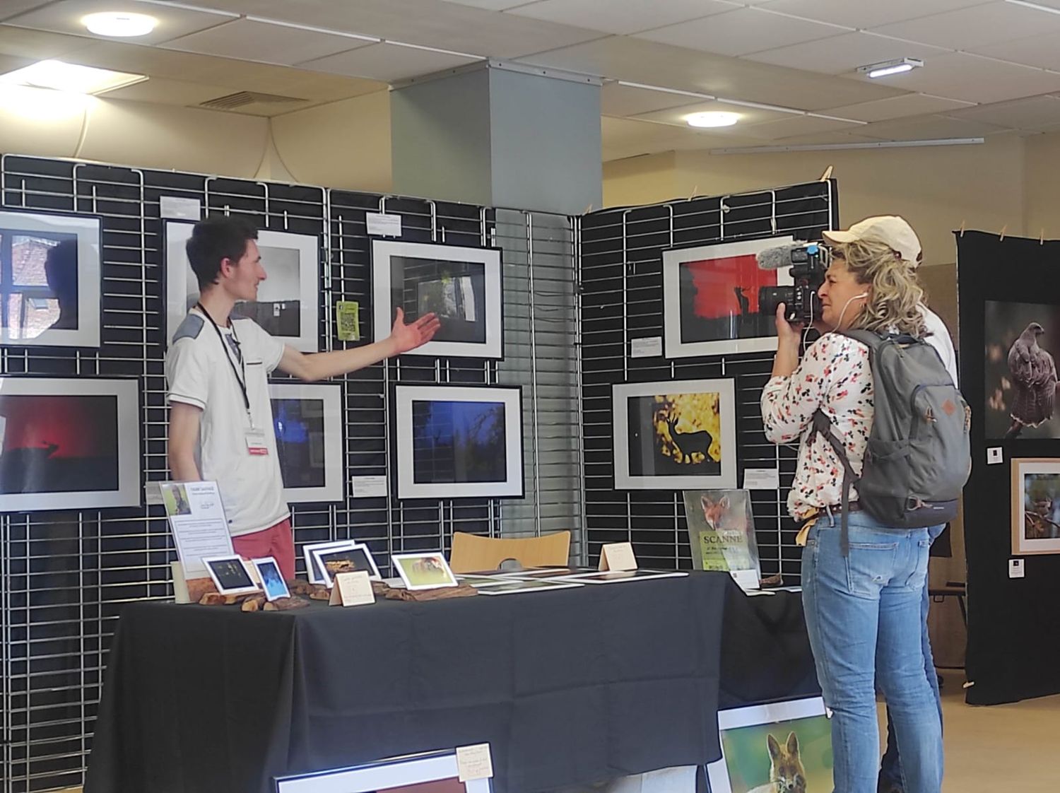 Photography exhibition booth with visitors viewing displayed artwork.