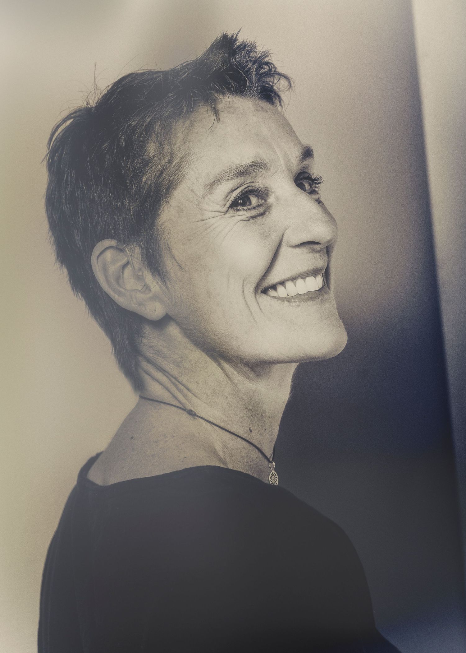 schwarz/ weiß Portrait einer Frau mit sehr kurzen Haaren, die lachend über ihre Schulter schaut im Fotostudio Aurelia Schulz in Bad Arolsen