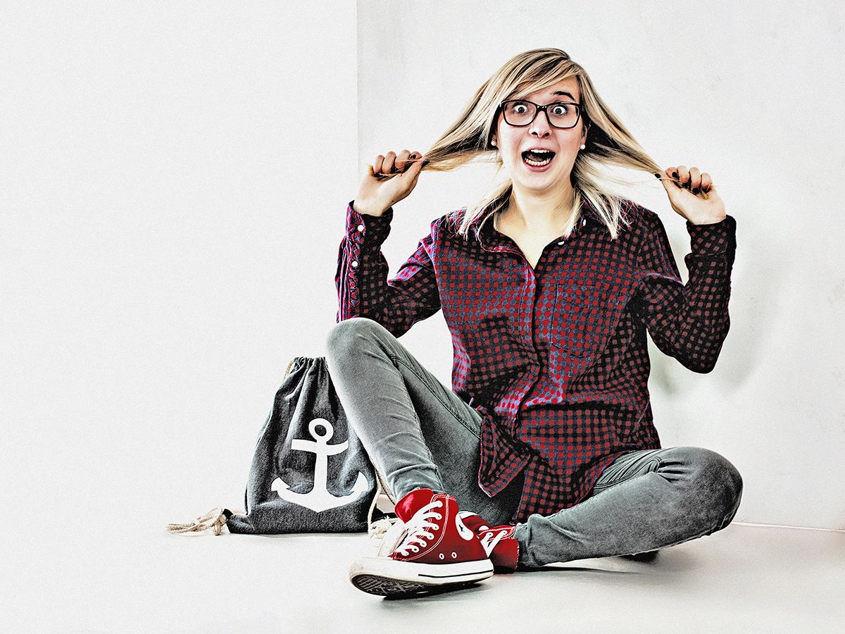 Lustiges Portrait einer jungen Frau, die sich an den Haaren zieht mit Chucks