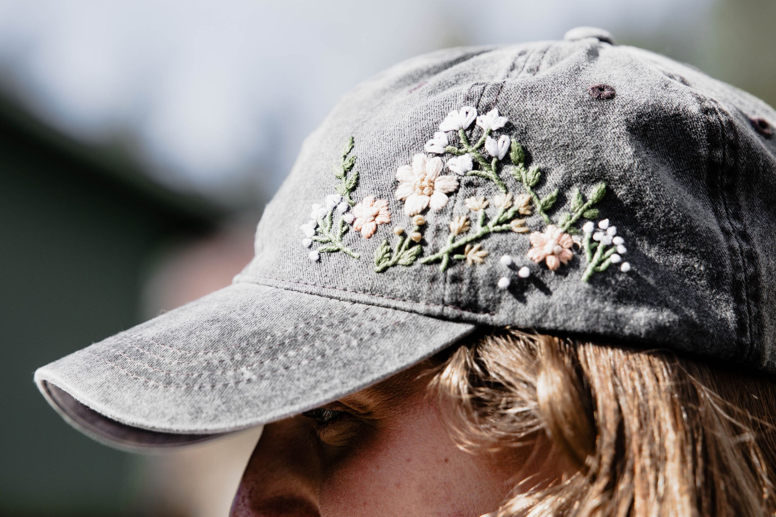 A worn gray baseball cap featuring delicate floral embroidery details on the side.