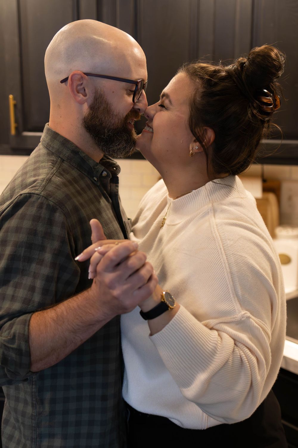 A romantic couple dancing together in an intimate embrace in their kitchen.