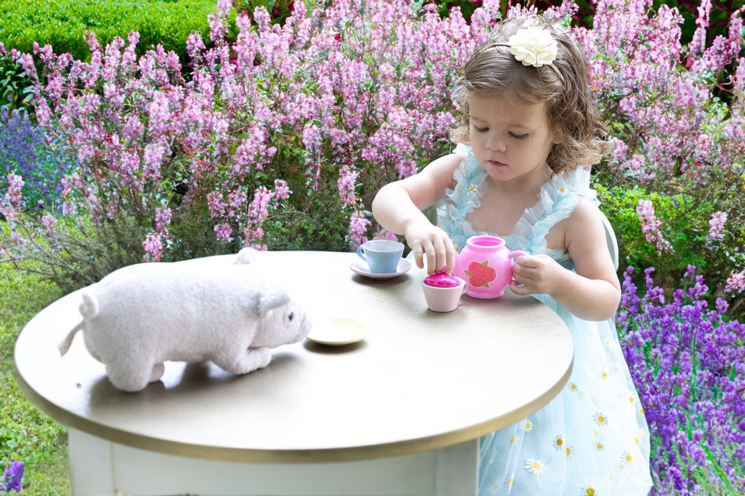 A tea party scene with stuffed animals and flowers in a garden.