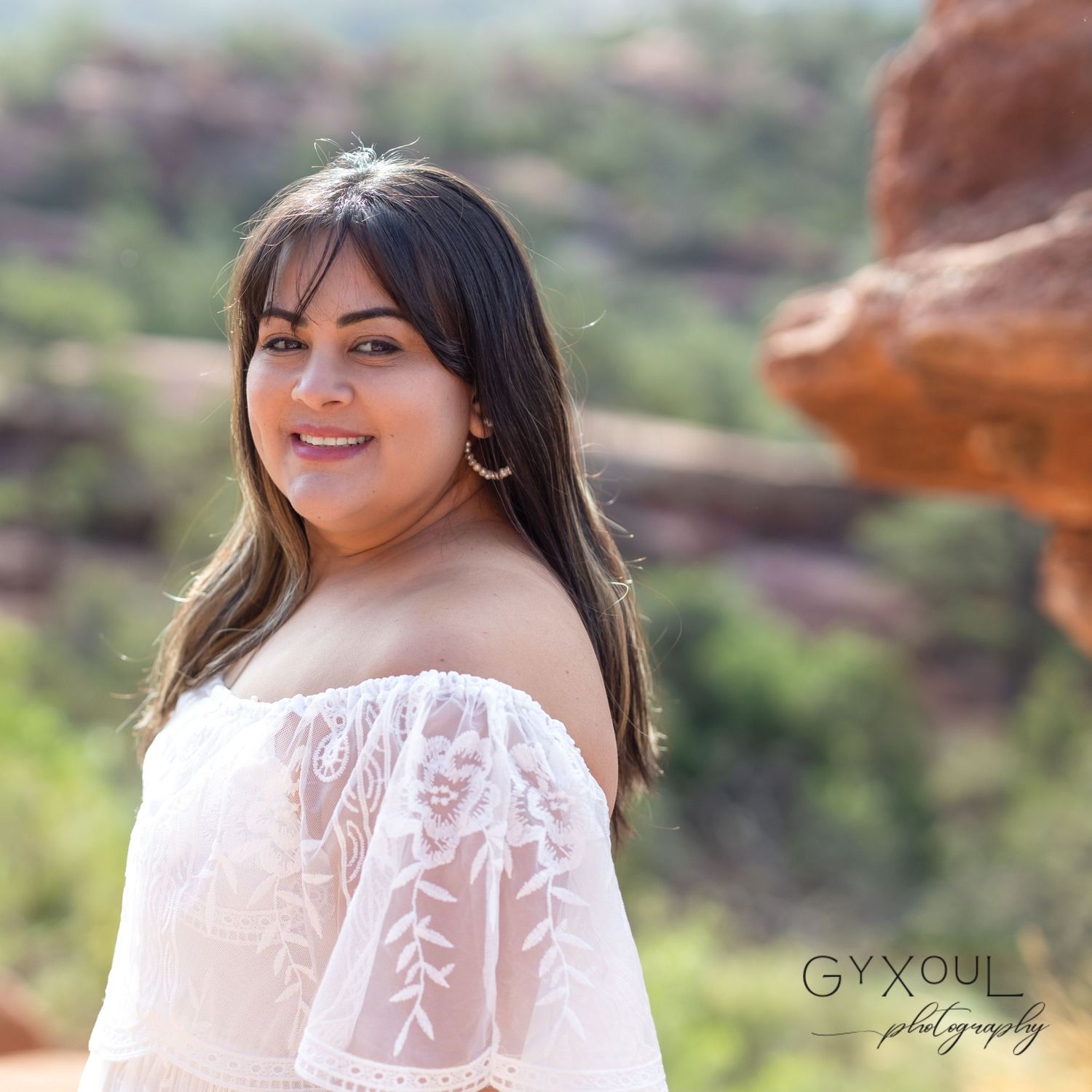 Portrait of woman in white lace dress against desert red rock background.