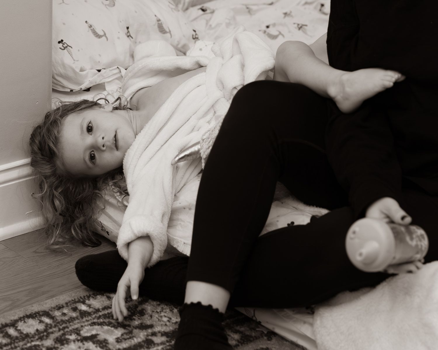 Black and white candid photo of playtime on bedroom floor.