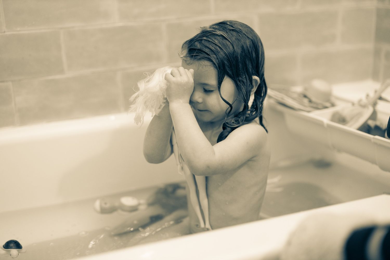 Sepia-toned bath time photo of child washing with soap.
