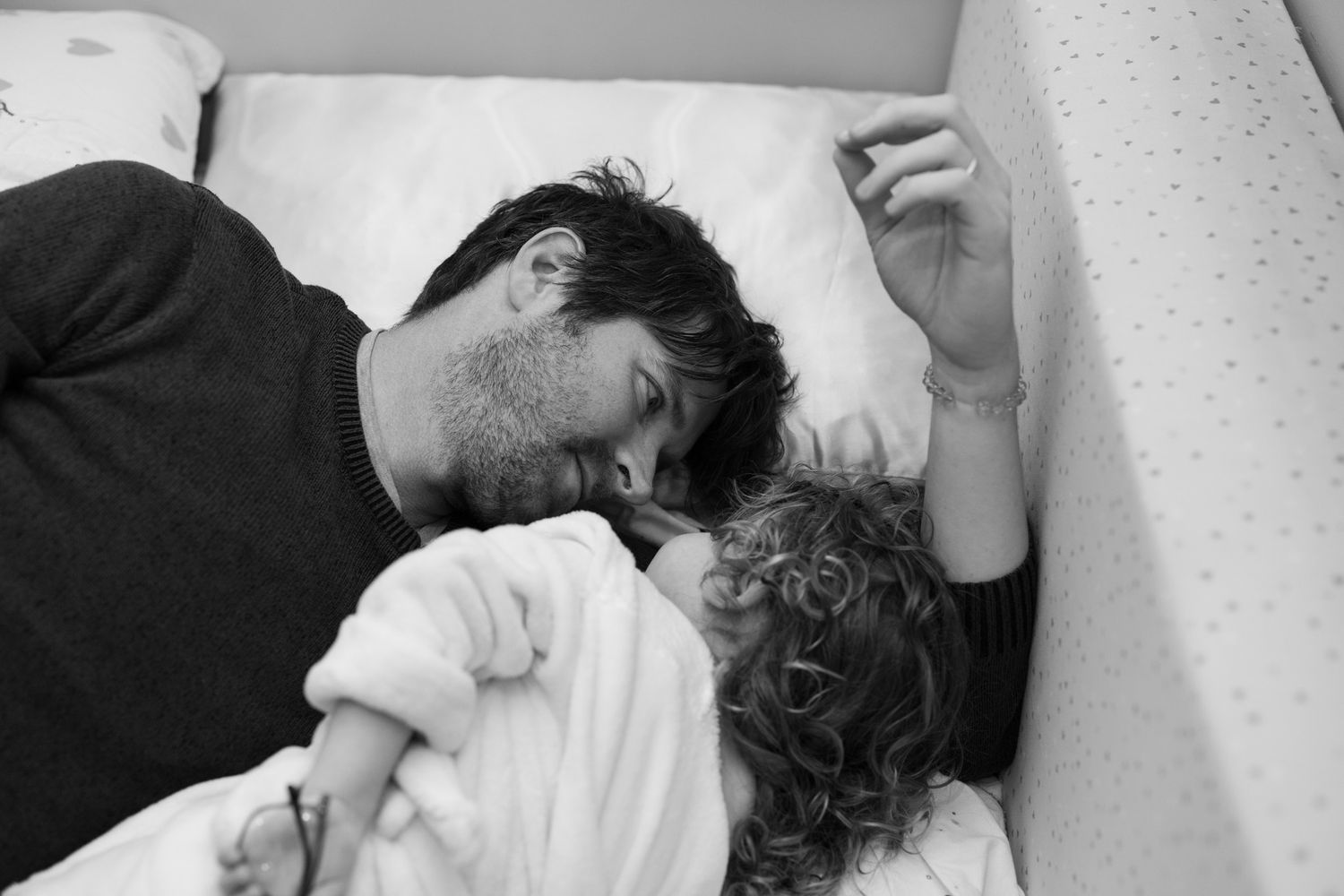 Tender black and white moment of rest time on white bedding.