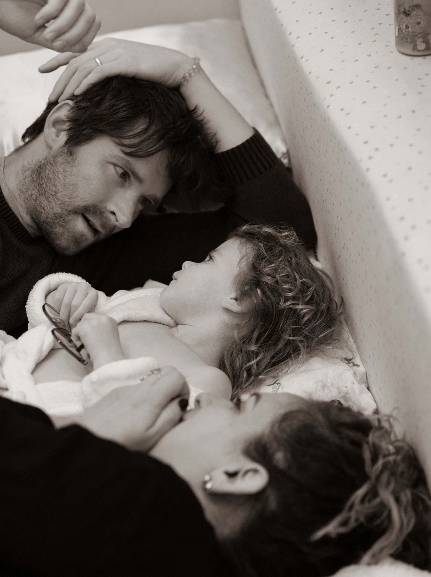 An intimate family moment captured in black and white as they rest together.