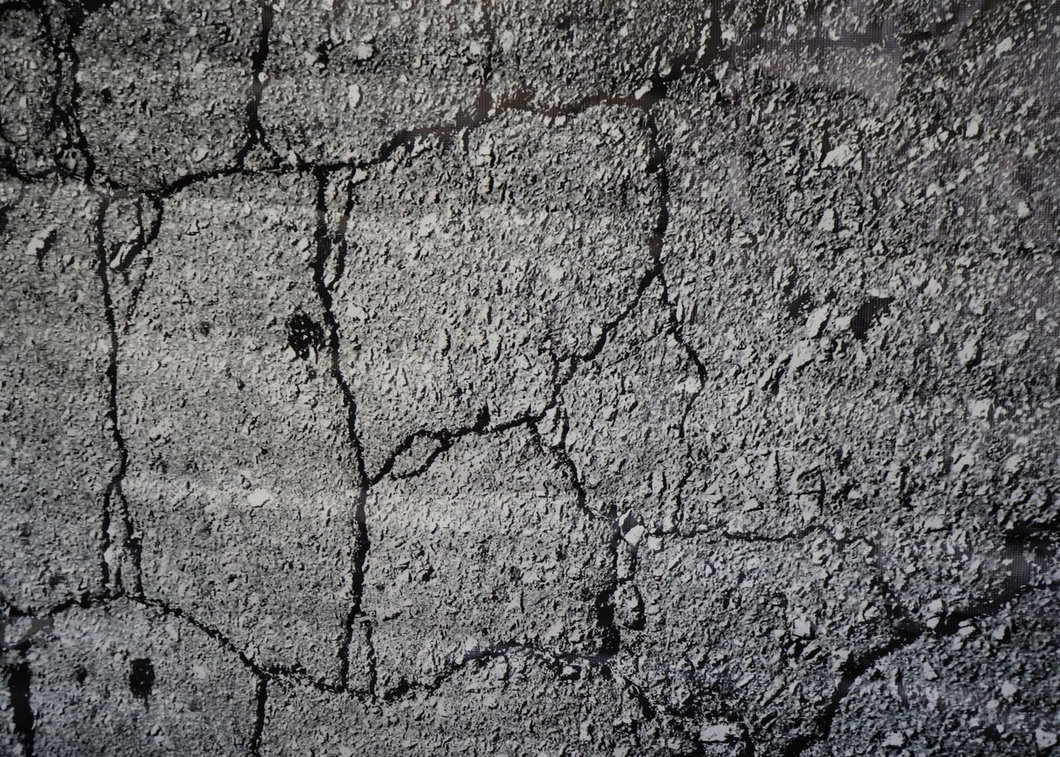 Cracked concrete wall texture with rough gray surface and deep fissures.
