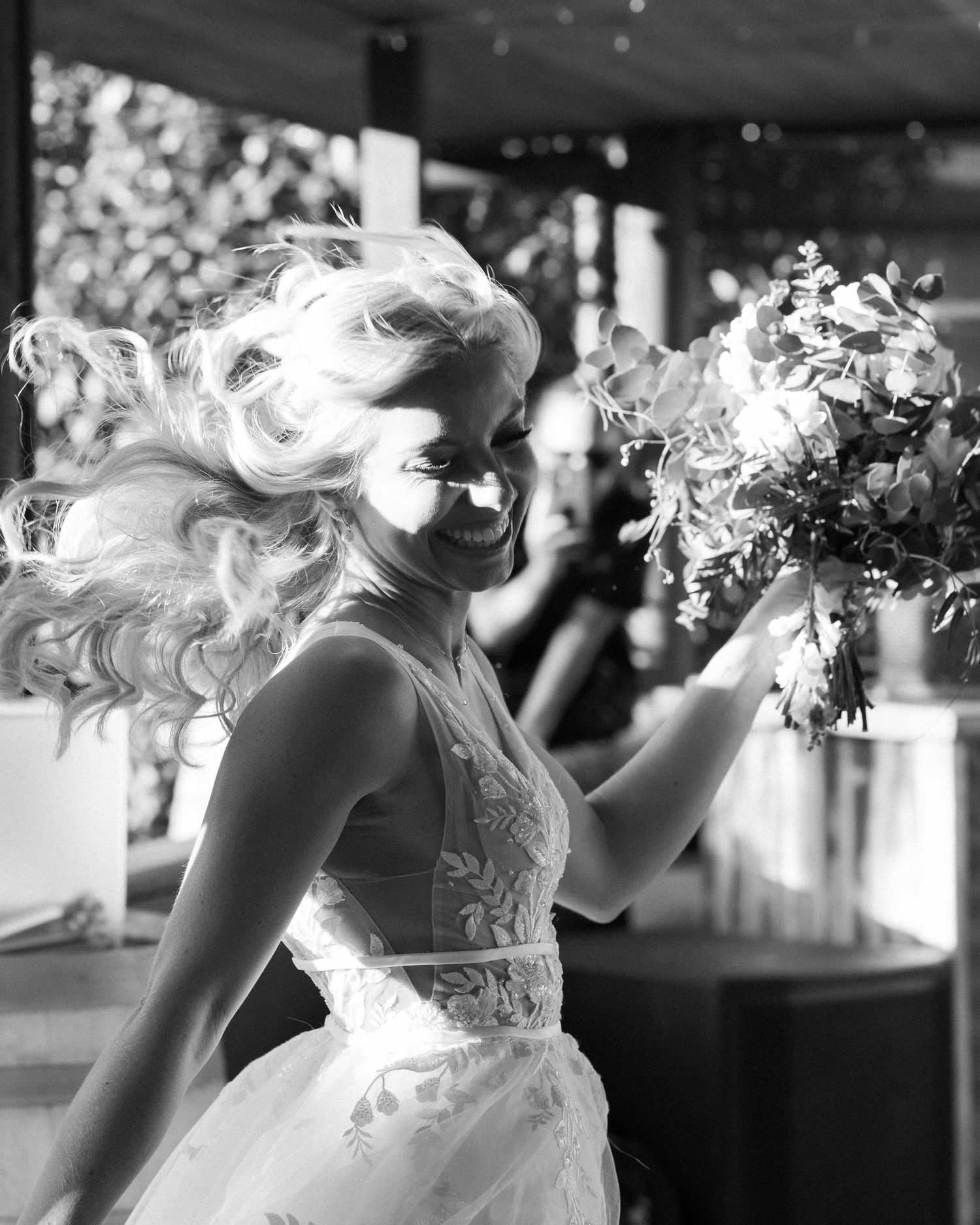 Black and white photo of bride twirling in lace dress during wedding reception.