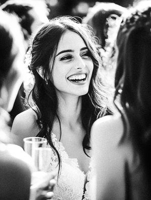 A candid black and white portrait of a bride laughing during wedding celebrations.