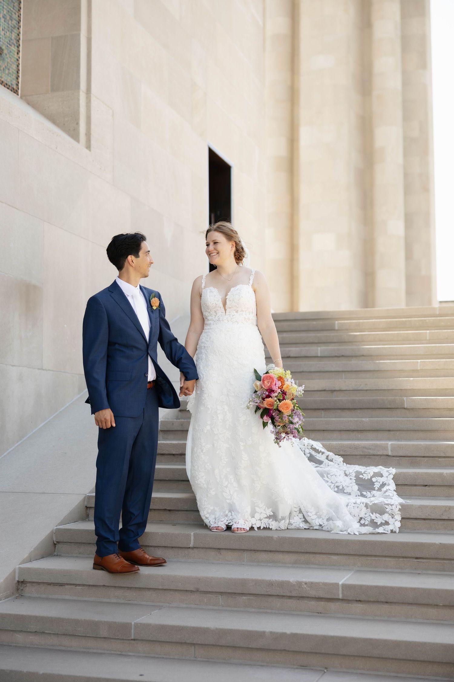 Newlywed couple sitting together on elegant stone steps during their wedding photo session.