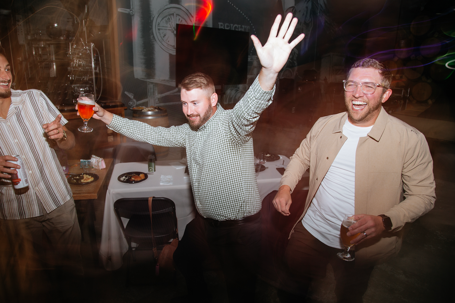 People dancing and having fun at a lively party with drinks and dim lighting.