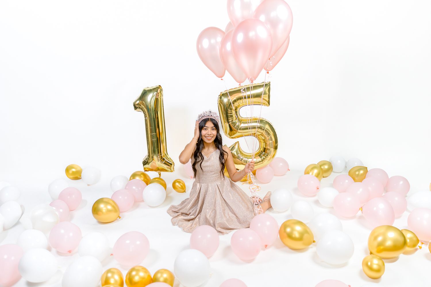 studio photoshoot of a 15 year old birthday girl holding her crown with balloons surrounding her in a Greeley Colorado studio