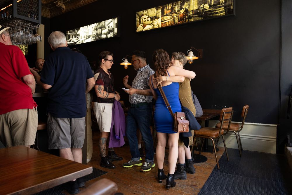 Interior of a busy bar or restaurant with people gathered in a dark atmospheric space.