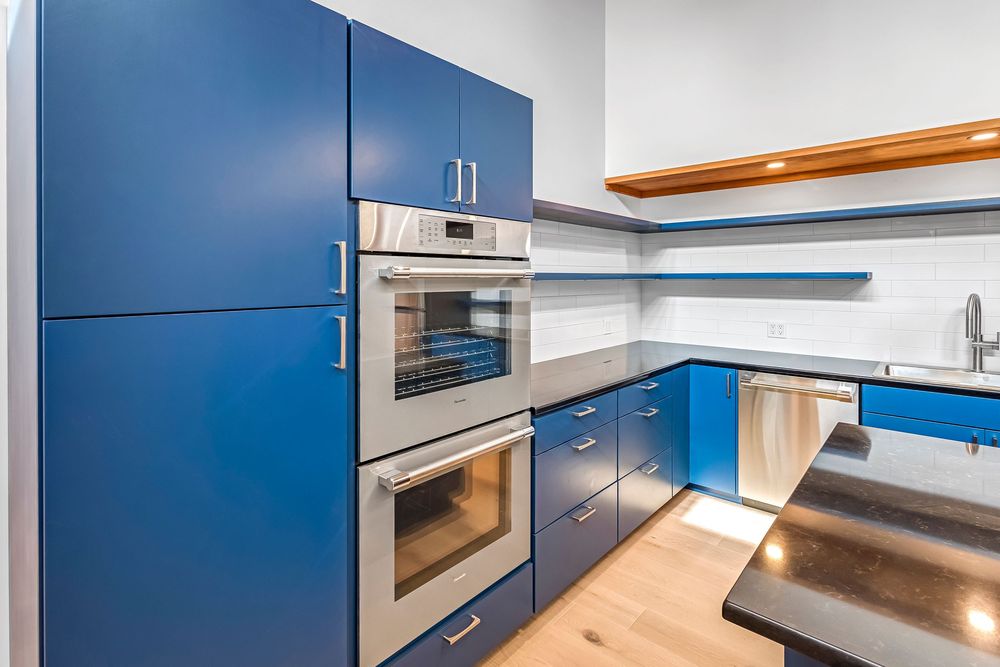 Contemporary blue kitchen featuring built-in appliances, floating shelves, and sleek cabinet design.