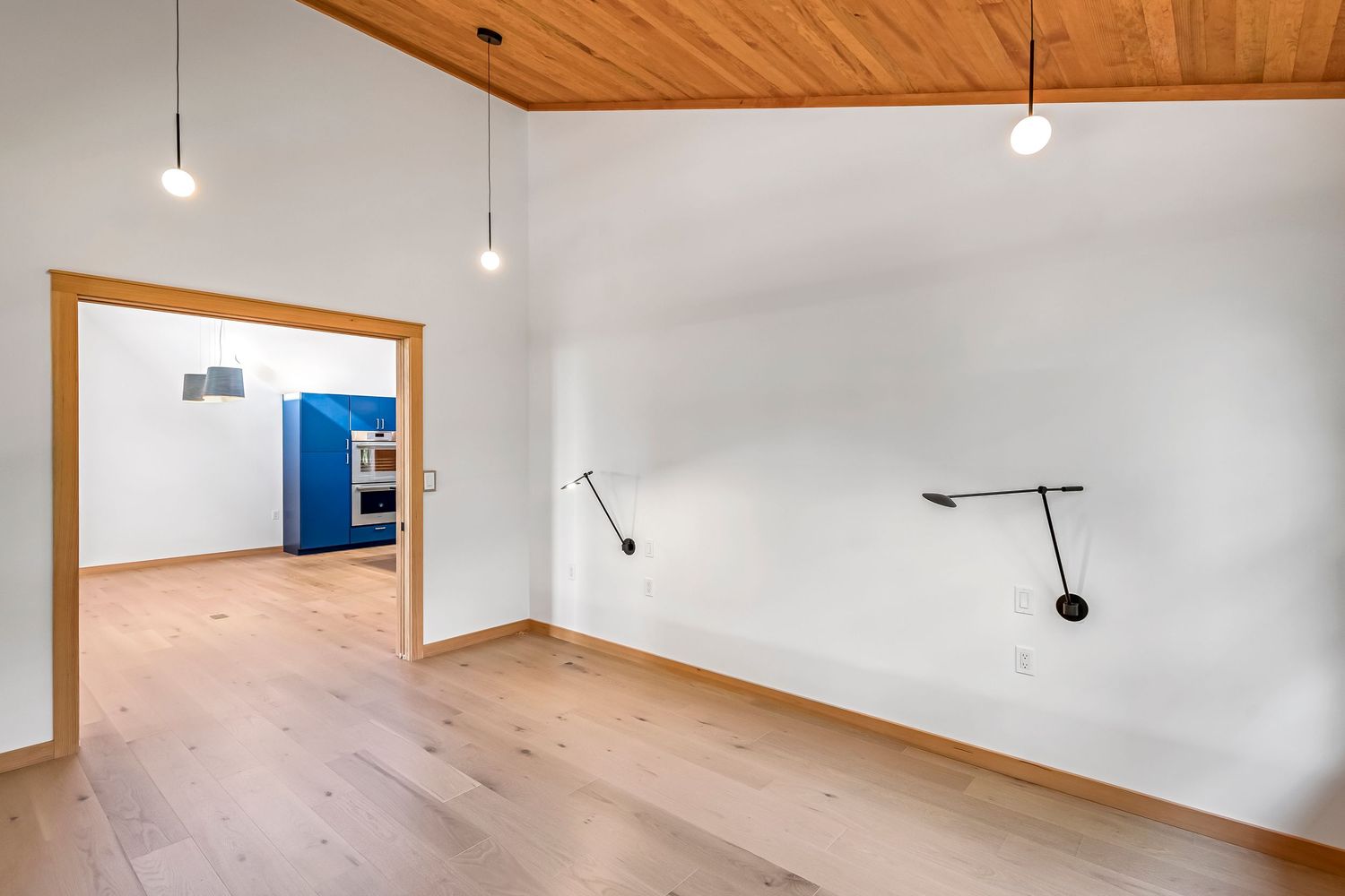 Minimalist room with wooden ceiling, white walls, and modern wall-mounted light fixtures.