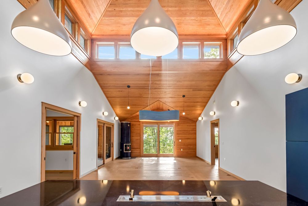 Dining area with vaulted wood ceiling, modern pendant lights, and large windows bringing in natural light.