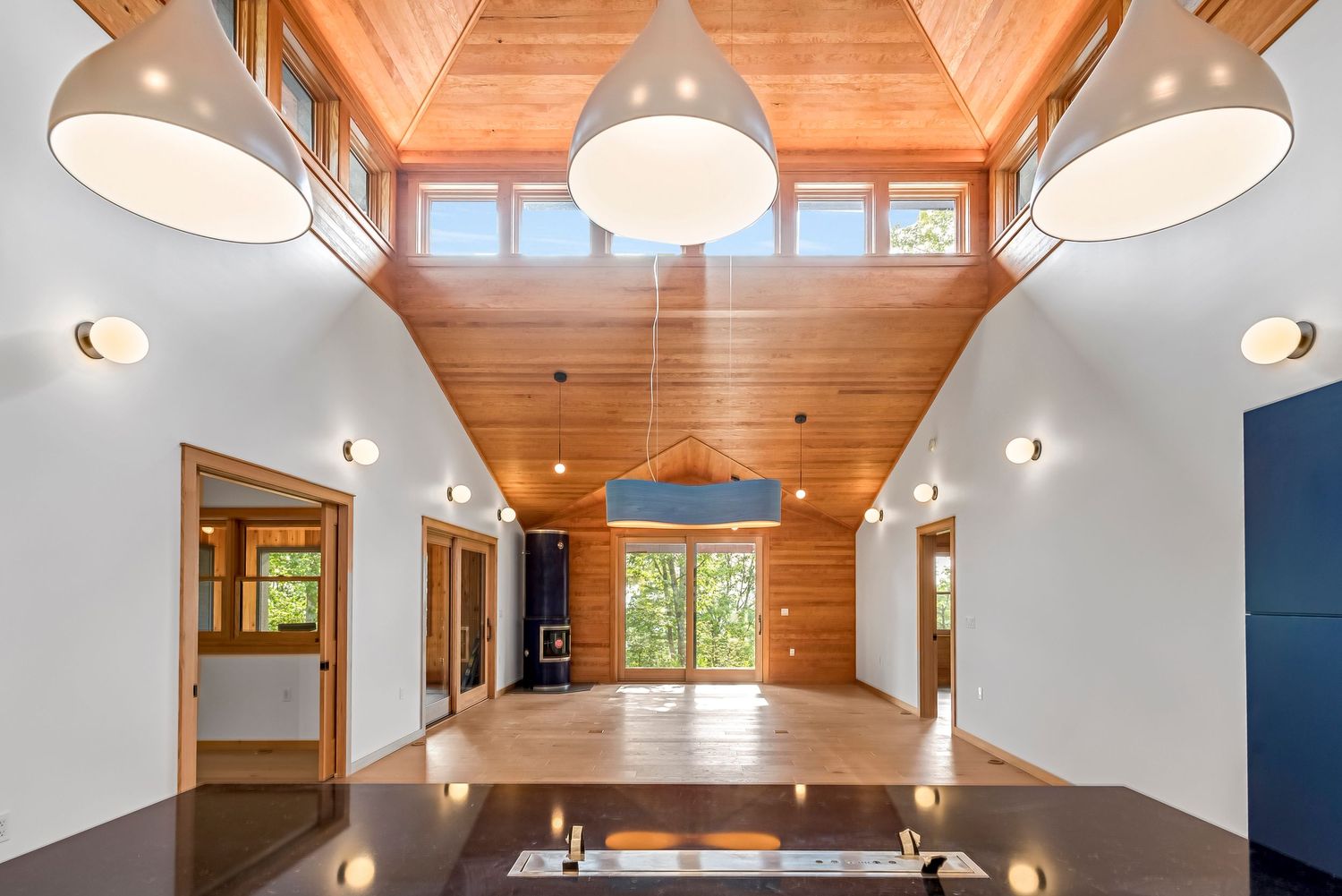 Dining area with vaulted wood ceiling, modern pendant lights, and large windows bringing in natural light.