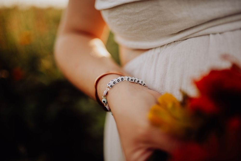 Close-up of a woman wearing a silver beaded bracelet while holding colorful flowers outdoors.