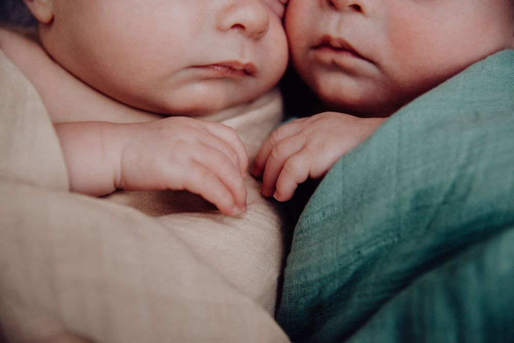 Two sleeping babies lying close together with fingers touching.
