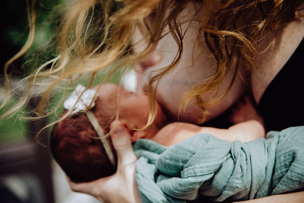 Intimate sleeping portrait with soft teal blanket and natural lighting.